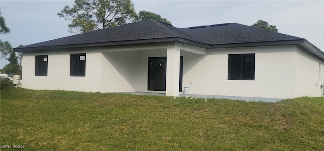 1215 Bayou St, Lehigh Acres, FL 33974 - back of house with roof with shingles, a yard, and stucco siding