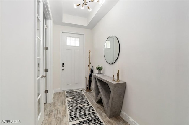 3240 Pilot Cir, Naples, FL 34120 - entryway featuring a chandelier, light wood-style floors, and a tray ceiling