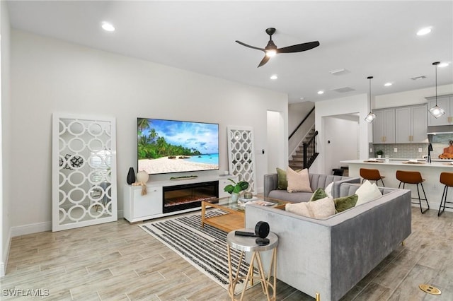3240 Pilot Cir, Naples, FL 34120 - living area with light wood finished floors, stairs, a ceiling fan, recessed lighting, and a glass covered fireplace