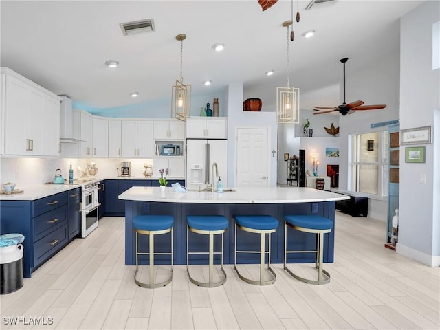 14891 Lake Olive Dr, Fort Myers, FL 33919 - kitchen featuring blue cabinetry, high end appliances, custom range hood, high vaulted ceiling, and light countertops