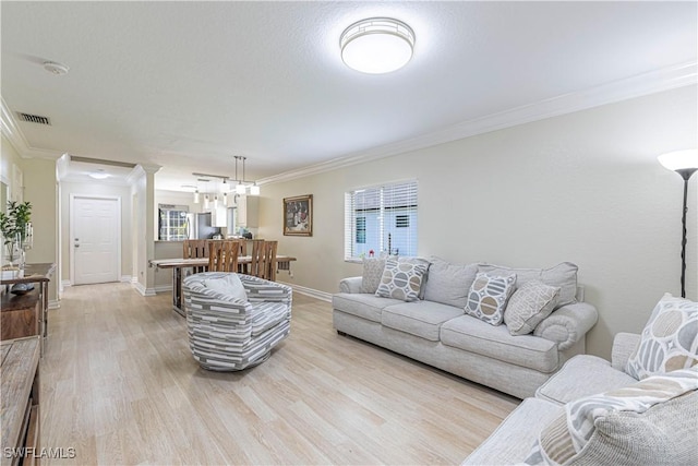1271 16th St NE, Naples, FL 34120 - living room featuring crown molding, light wood-type flooring, a chandelier, and healthy amount of natural light