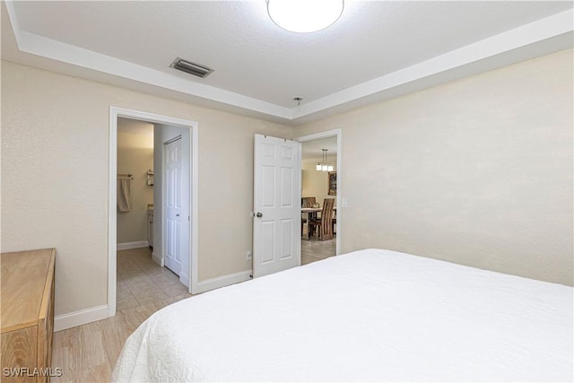 1271 16th St NE, Naples, FL 34120 - bedroom with a tray ceiling, light wood-style flooring, and connected bathroom