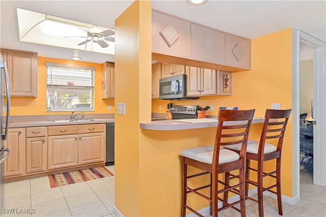 4217 SE 19th Ave Unit 110, Cape Coral, FL 33904 - kitchen featuring stainless steel appliances, a kitchen breakfast bar, light brown cabinets, ceiling fan, and light tile patterned floors
