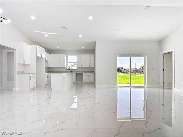 5001 Bywood St, Lehigh Acres, FL 33971 - kitchen with light marble finish flooring, recessed lighting, open floor plan, a kitchen island, and white cabinets
