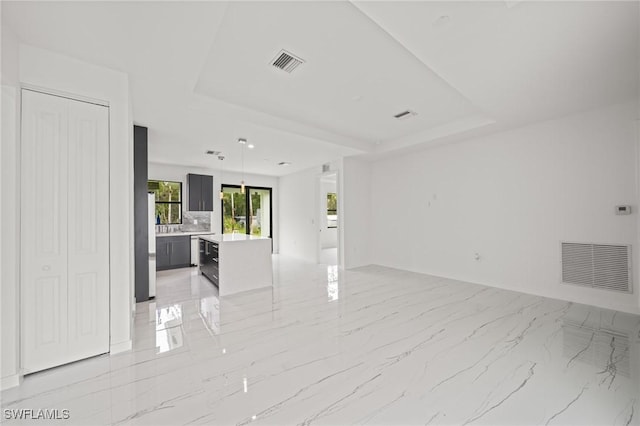 3525 43rd Ave NE, Naples, FL 34120 - unfurnished living room featuring a tray ceiling and light marble finish floors
