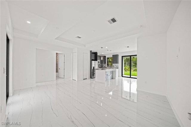 3525 43rd Ave NE, Naples, FL 34120 - unfurnished living room featuring a raised ceiling, recessed lighting, and light marble finish flooring
