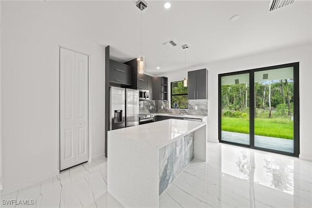 3525 43rd Ave NE, Naples, FL 34120 - kitchen featuring modern cabinets, stainless steel appliances, light marble finish flooring, tasteful backsplash, and decorative light fixtures