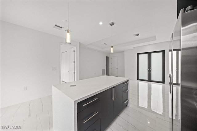 3525 43rd Ave NE, Naples, FL 34120 - kitchen with freestanding refrigerator, a raised ceiling, dark cabinets, light marble finish floors, and light countertops