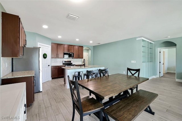 692 Hadley St E, Naples, FL 34104 - dining area with arched walkways, light wood-style flooring, and recessed lighting