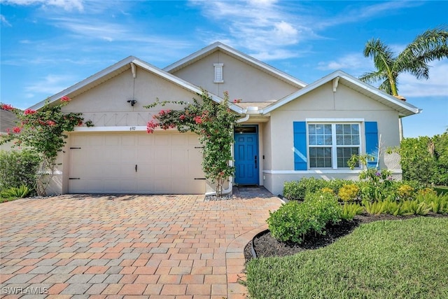 692 Hadley St E, Naples, FL 34104 - view of front of home with stucco siding, an attached garage, and decorative driveway