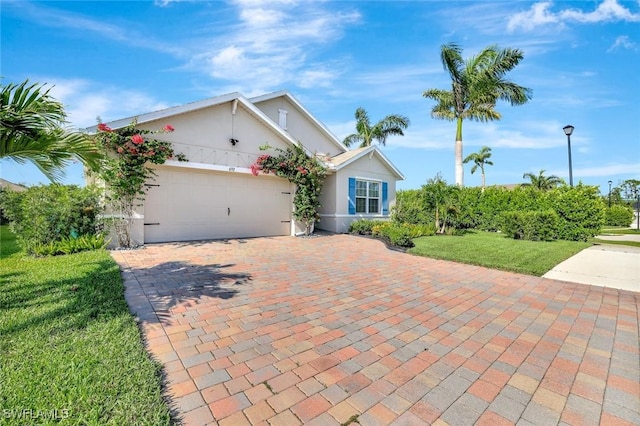 692 Hadley St E, Naples, FL 34104 - single story home featuring an attached garage, decorative driveway, stucco siding, and a front yard