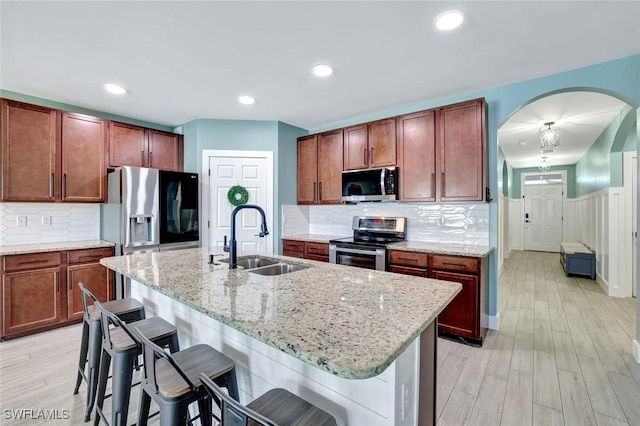 692 Hadley St E, Naples, FL 34104 - kitchen with stainless steel appliances, a kitchen breakfast bar, light stone countertops, light wood finished floors, and wainscoting