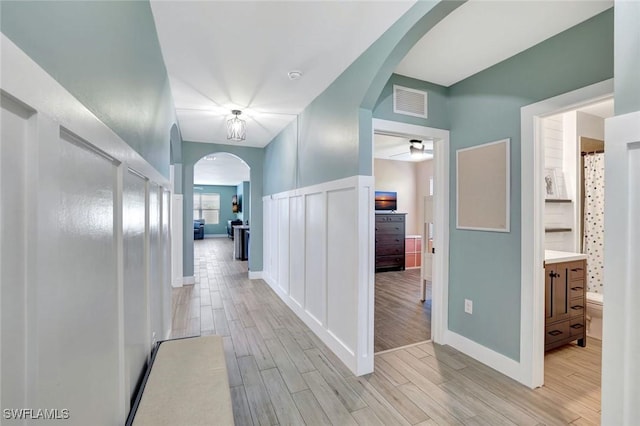 692 Hadley St E, Naples, FL 34104 - hall with arched walkways, light wood-type flooring, and wainscoting