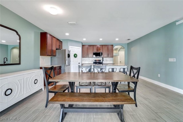 692 Hadley St E, Naples, FL 34104 - dining area featuring arched walkways, light wood-style flooring, and recessed lighting