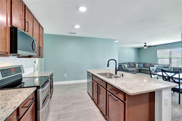 692 Hadley St E, Naples, FL 34104 - kitchen with stainless steel appliances, ceiling fan, a center island with sink, light stone counters, and open floor plan