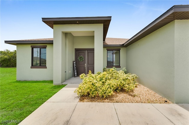 2622 SW 5th St, Cape Coral, FL 33991 - entrance to property with stucco siding, a yard, and roof with shingles