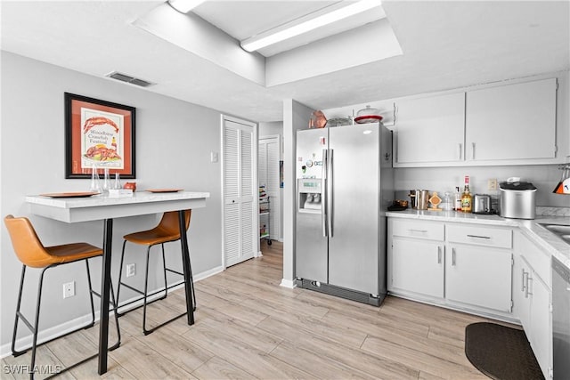 9761 Maplecrest Cir, Lehigh Acres, FL 33936 - kitchen with stainless steel refrigerator with ice dispenser, light countertops, light wood-style floors, white cabinetry, and dishwashing machine