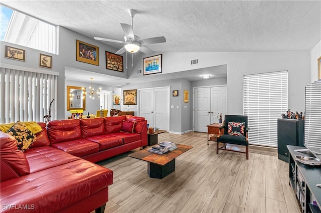 9761 Maplecrest Cir, Lehigh Acres, FL 33936 - living room featuring ceiling fan, a chandelier, a textured ceiling, light wood-style floors, and high vaulted ceiling
