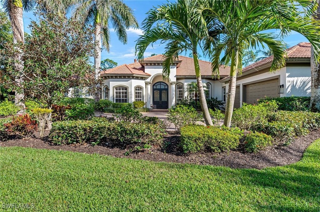 7610 Palmer Ct, Naples, FL 34113 - mediterranean / spanish house featuring stucco siding, an attached garage, a tiled roof, and a front yard