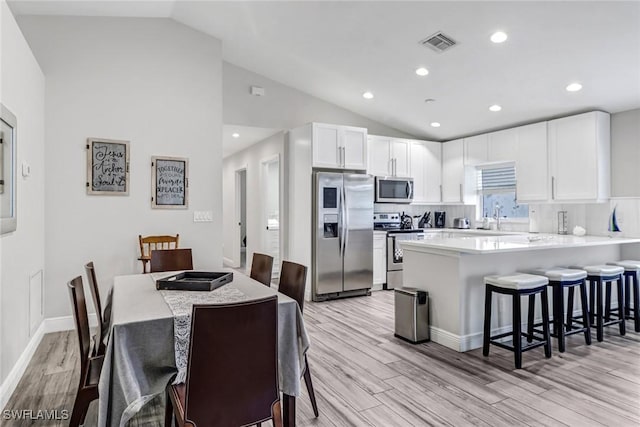 851 102nd Ave N, Naples, FL 34108 - kitchen featuring appliances with stainless steel finishes, light wood-style flooring, a kitchen breakfast bar, white cabinets, and recessed lighting