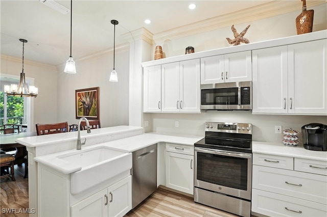 700 L Ambiance Cir Unit 202, Naples, FL 34108 - kitchen featuring appliances with stainless steel finishes, crown molding, a chandelier, a peninsula, and light countertops