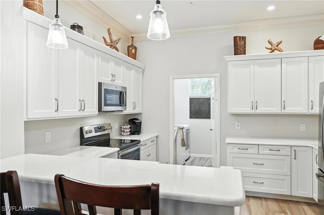 700 L Ambiance Cir Unit 202, Naples, FL 34108 - kitchen featuring stainless steel appliances, independent washer and dryer, a breakfast bar, white cabinets, and a peninsula