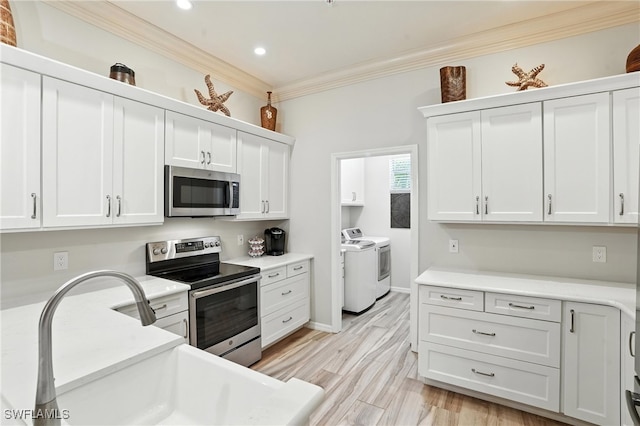 700 L Ambiance Cir Unit 202, Naples, FL 34108 - kitchen featuring appliances with stainless steel finishes, independent washer and dryer, ornamental molding, white cabinets, and light countertops