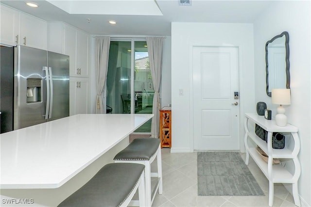5467 Double Eagle Cir Unit 3212, Ave Maria, FL 34142 - kitchen featuring stainless steel fridge, a breakfast bar, light countertops, white cabinetry, and light tile patterned floors