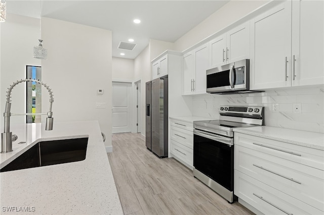 1159 SW 5th Ter, Cape Coral, FL 33991 - kitchen with stainless steel appliances, white cabinetry, backsplash, light stone countertops, and recessed lighting