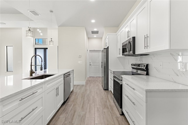 1159 SW 5th Ter, Cape Coral, FL 33991 - kitchen featuring appliances with stainless steel finishes, white cabinetry, recessed lighting, hanging light fixtures, and backsplash