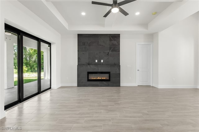 1159 SW 5th Ter, Cape Coral, FL 33991 - unfurnished living room featuring a tray ceiling, a ceiling fan, recessed lighting, a tile fireplace, and light wood-style floors