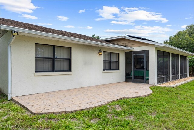 27780 Matheson Ave, Bonita Springs, FL 34135 - rear view of property featuring a sunroom, a patio, a lawn, and stucco siding