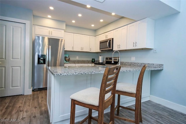 8849 Somerset Blvd, Fort Myers, FL 33919 - kitchen featuring appliances with stainless steel finishes, light stone countertops, dark wood finished floors, white cabinets, and recessed lighting