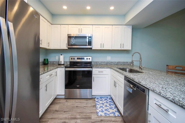8849 Somerset Blvd, Fort Myers, FL 33919 - kitchen featuring appliances with stainless steel finishes, light wood-style floors, white cabinets, light stone countertops, and recessed lighting