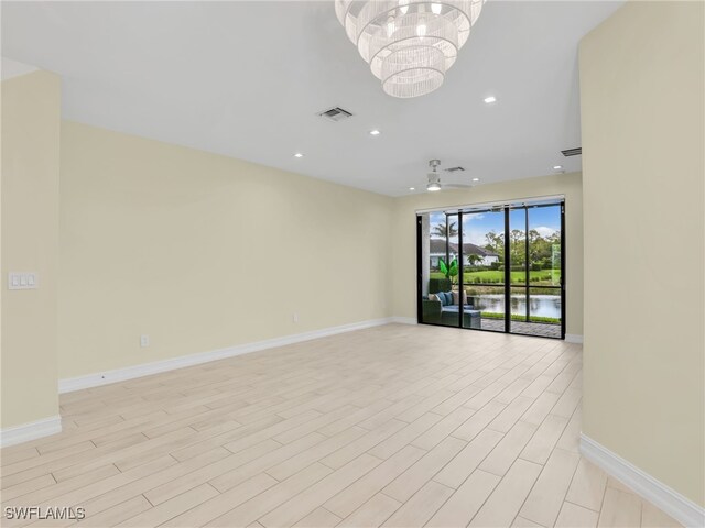 7524 Carnegie Way, Naples, FL 34119 - unfurnished room with a chandelier, recessed lighting, light wood-style floors, and a water view