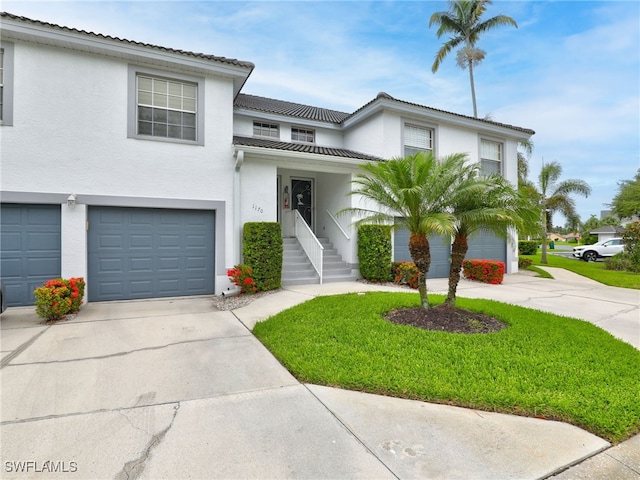 1170 Partridge Ln Unit 202, Naples, FL 34104 - townhome / multi-family property with driveway, stucco siding, an attached garage, and a front yard