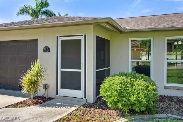718 Coral Dr, Cape Coral, FL 33904 - view of exterior entry with stucco siding, a shingled roof, and a garage