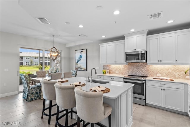 2609 Seychelles Cir Unit 1603, Naples, FL 34112 - kitchen featuring stainless steel appliances, light countertops, tasteful backsplash, a breakfast bar area, and an island with sink