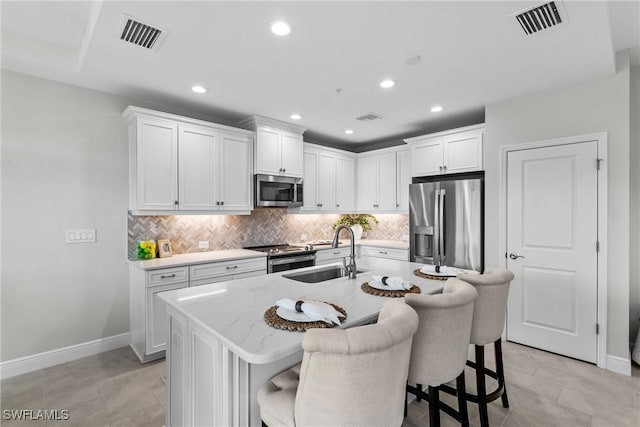 2609 Seychelles Cir Unit 1603, Naples, FL 34112 - kitchen featuring appliances with stainless steel finishes, decorative backsplash, white cabinetry, a kitchen breakfast bar, and recessed lighting