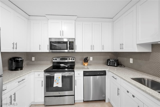 7400 College Pkwy Unit 59C, Fort Myers, FL 33907 - kitchen with appliances with stainless steel finishes, white cabinetry, tasteful backsplash, and light stone countertops
