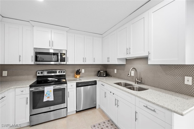7400 College Pkwy Unit 59C, Fort Myers, FL 33907 - kitchen featuring stainless steel appliances, white cabinetry, light tile patterned floors, decorative backsplash, and light stone countertops