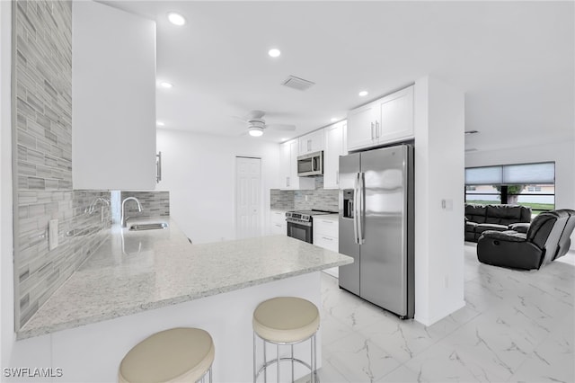 1506 SE 42nd St, Cape Coral, FL 33904 - kitchen with stainless steel appliances, backsplash, a peninsula, light stone countertops, and white cabinetry