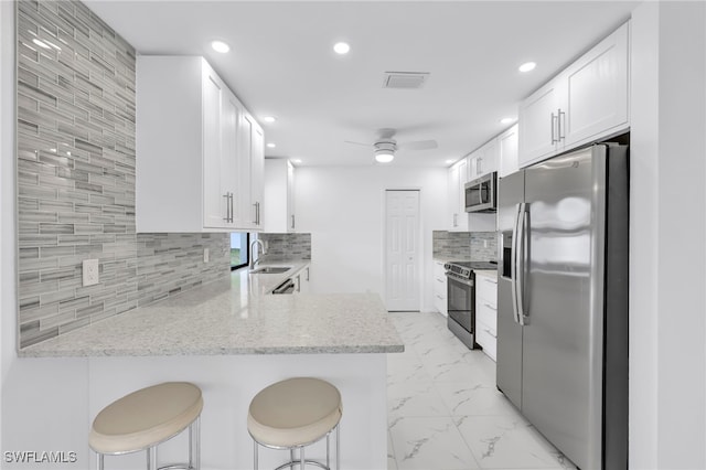 1506 SE 42nd St, Cape Coral, FL 33904 - kitchen with stainless steel appliances, light marble finish floors, a peninsula, backsplash, and white cabinetry