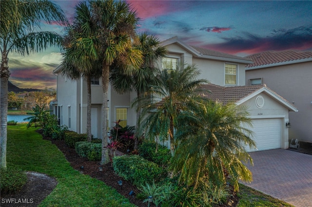 10298 Carolina Willow Dr, Fort Myers, FL 33913 - property exterior at dusk featuring decorative driveway, stucco siding, and an attached garage