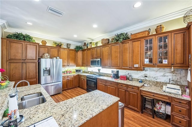 1841 Senegal Date Dr, Naples, FL 34119 - kitchen featuring stainless steel appliances, brown cabinetry, light wood-style flooring, light stone counters, and crown molding
