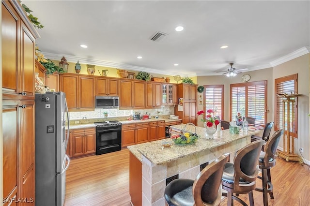 1841 Senegal Date Dr, Naples, FL 34119 - kitchen featuring stainless steel appliances, brown cabinetry, a kitchen bar, light wood finished floors, and decorative backsplash