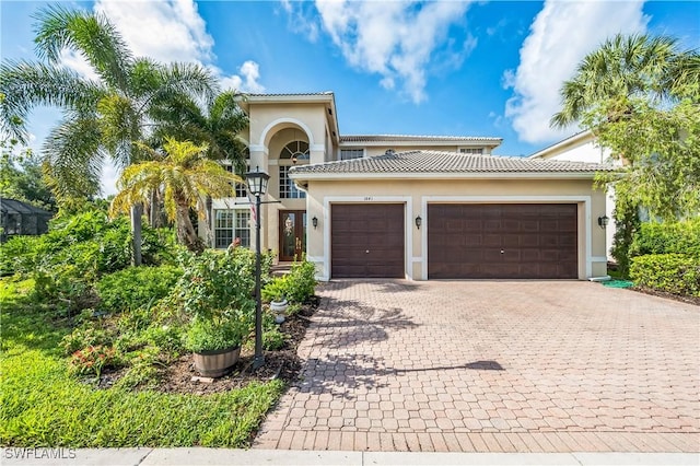 1841 Senegal Date Dr, Naples, FL 34119 - mediterranean / spanish home featuring stucco siding, decorative driveway, an attached garage, and a tiled roof