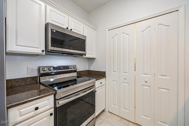 12980 Positano Cir Unit 306, Naples, FL 34105 - kitchen with appliances with stainless steel finishes, white cabinetry, dark stone countertops, and light tile patterned floors