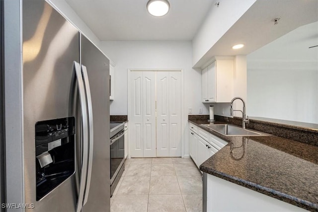 12980 Positano Cir Unit 306, Naples, FL 34105 - kitchen featuring stainless steel appliances, white cabinetry, light tile patterned floors, a peninsula, and dark stone countertops