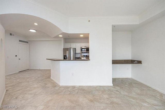 12980 Positano Cir Unit 306, Naples, FL 34105 - kitchen featuring stainless steel appliances, white cabinets, dark countertops, arched walkways, and crown molding